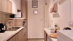 A modern kitchen with wooden cabinets, a stainless steel sink, and a clock on the wall. - Santamaura86 Apartment (Roma)
