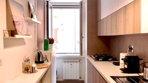 A modern kitchen with a window, white cabinets, a gas stove, and a coffee maker. - Santamaura86 Apartment (Roma)