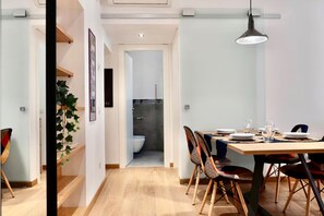 A modern dining area with a wooden table, chairs, and a hanging pendant light. A bathroom is visible through an open door in the background. - Santamaura86 Apartment (Roma)