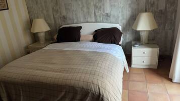 Une chambre à coucher avec un lit, deux tables de chevet, une commode, un tableau au mur et un rideau à rayures.