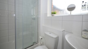 A modern bathroom with a glass shower enclosure, a toilet, and a sink with a mirror above it. - This is the One bright central 1BR well equiped. (Bedford)