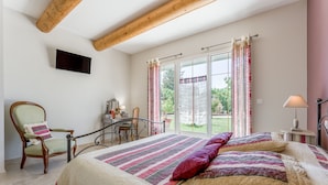 A bedroom with a bed, a chair, a desk, and a television. - "Frédéric Mistral" Room at La Bastide des Mereuilles with Private Terrace, Wi-Fi & AC (Orange)