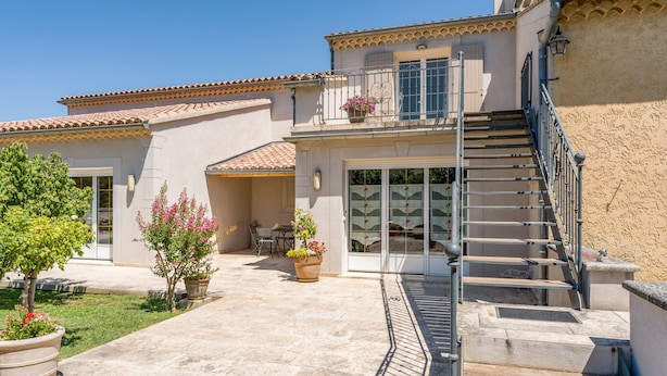 A two-story building with a tiled roof, a balcony with metal railings, and a staircase leading to the upper floor. - "Frédéric Mistral" Room at La Bastide des Mereuilles with Private Terrace, Wi-Fi & AC (Orange)