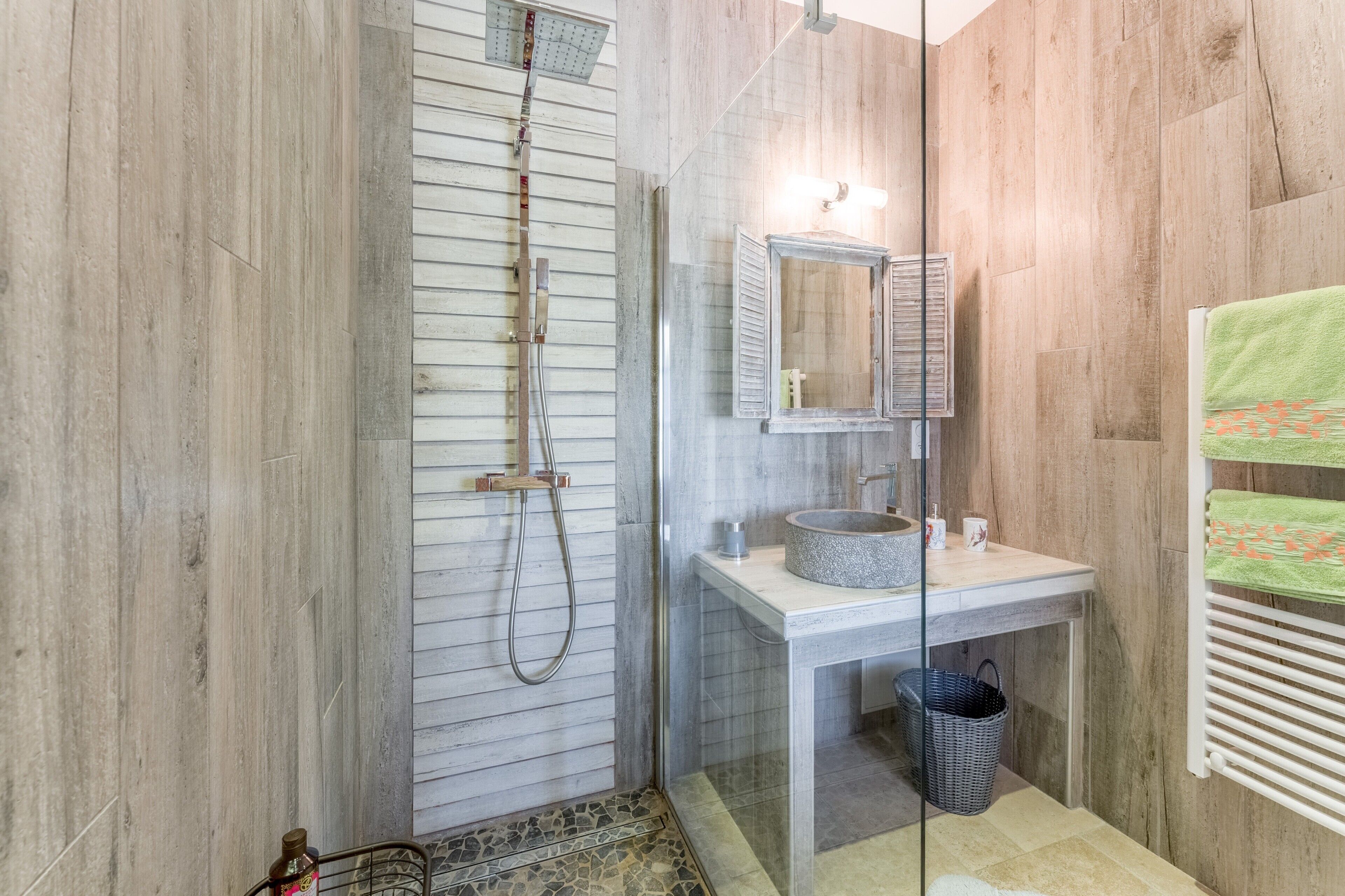 A bathroom with a shower, a sink with a mirror, and a towel rack.