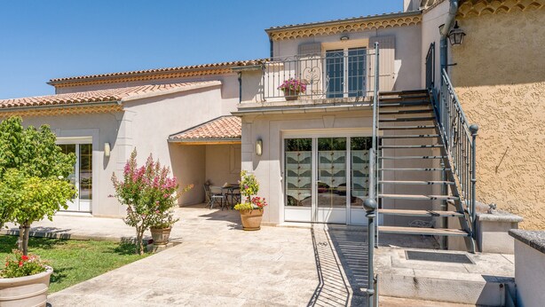 A two-story building with a tiled roof, a balcony with metal railings, and a staircase leading to the upper floor. - "Marcel Pagnol" Room at La Bastide des Mereuilles with Private Terrace, Wi-Fi & AC (Orange)