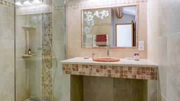Une salle de bain avec une douche à parois de verre, un lavabo avec un miroir et un mur recouvert de carreaux.