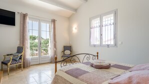 A bedroom with a bed, a chair, a window, and a balcony. - "Marcel Pagnol" Room at La Bastide des Mereuilles with Private Terrace, Wi-Fi & AC (Orange)
