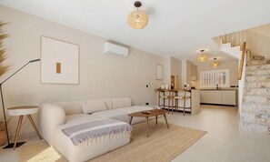 A modern living room with a sofa, coffee table, and a dining area with chairs.
