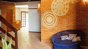 A staircase leading to a second floor, a round blue seating area with patterned cushions, and a potted plant. - villa uca frances (Marechal Deodoro)