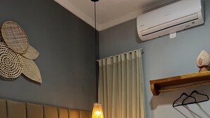 A hotel room with a bed, a hanging lamp, a window with curtains, and an air conditioning unit. - villa uca frances (Marechal Deodoro)
