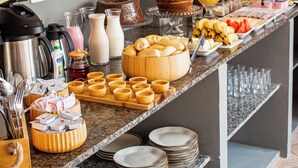 A buffet setup with various food items, a coffee maker, and decorative mirrors on the wall. - villa uca frances (Marechal Deodoro)