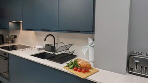 Une cuisine moderne avec des meubles bleu foncé, un évier noir et un grille-pain.