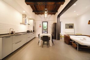 A compact hotel room with a kitchenette, a dining area, and a bed.
