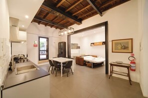 A modern kitchen with a dining area, a bed, and a fire extinguisher. - BuddyRent - Golden House - Patio - Monti - 7 (Roma)