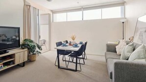 Una sala moderna con comedor, televisor de pantalla plana y sofá gris.