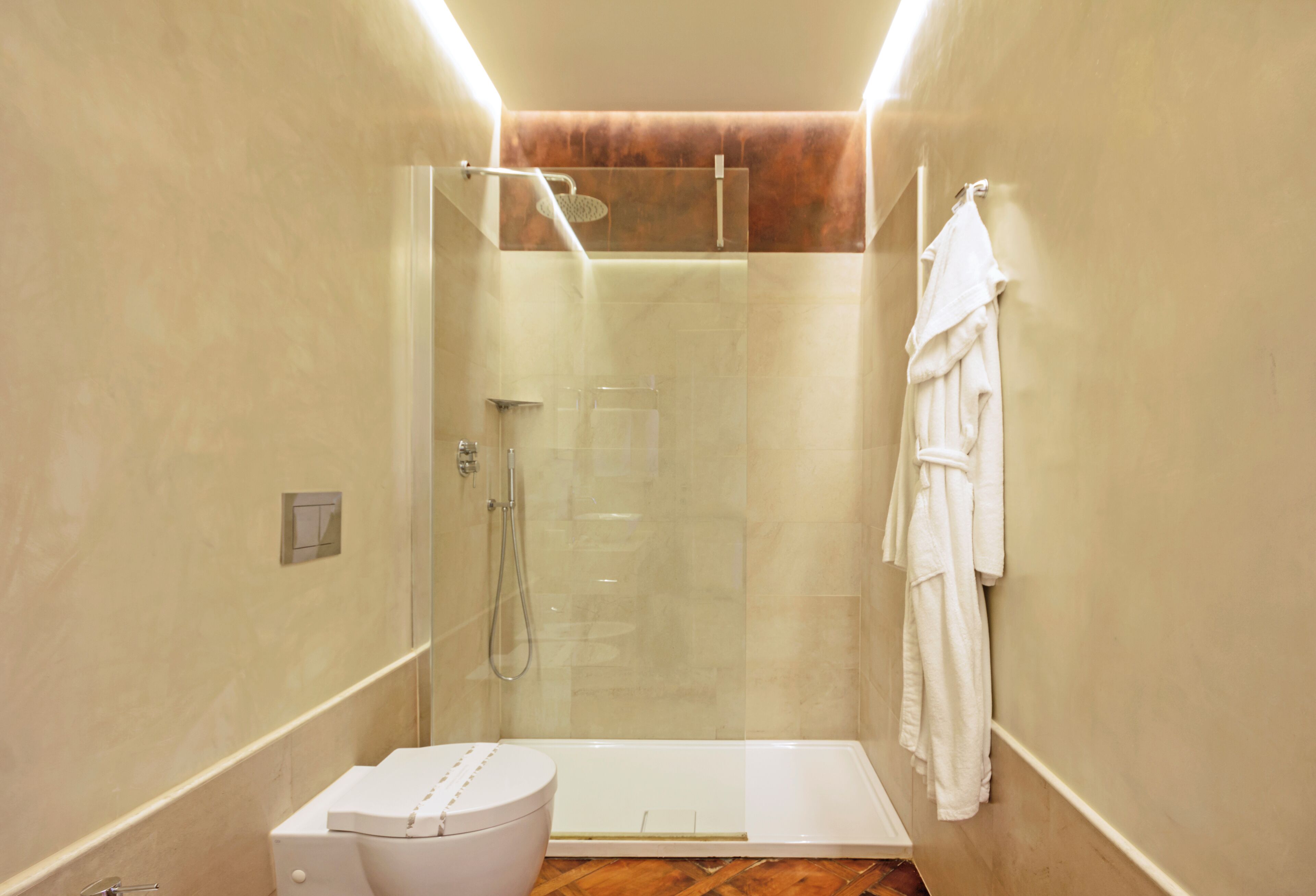 Ein modernes Badezimmer mit einer einteiligen Duschkabine, einer weißen Toilette und einem Handtuch an der Wand.
