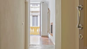 A hallway with a light-colored floor and walls, leading to a balcony with yellow railings. - SUYTE Torino Centro (Turin)