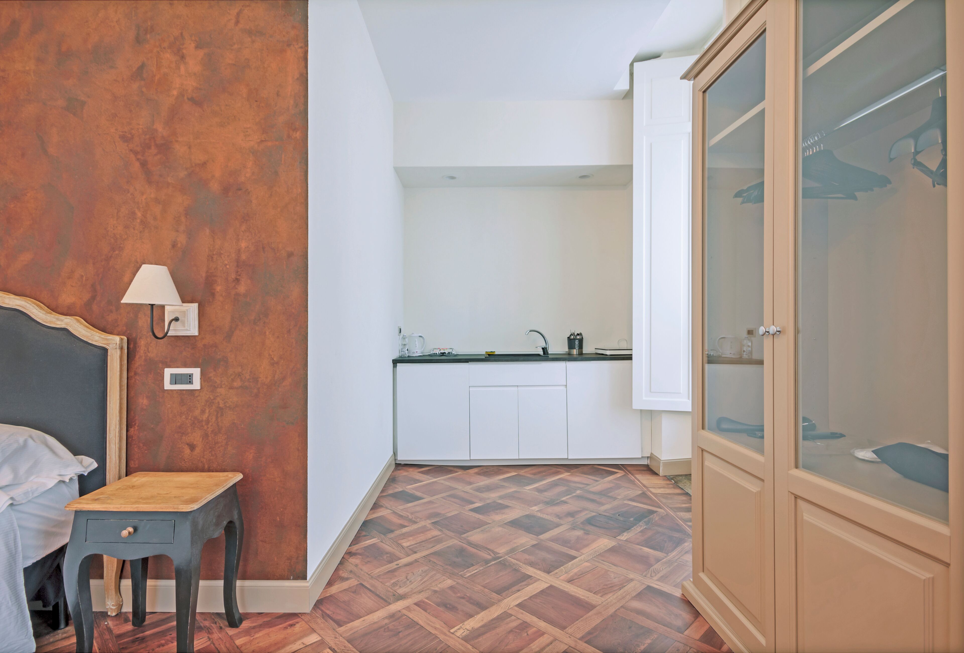 Ein Schlafzimmer mit Bett, Nachttisch, Lampe und Kleiderschrank.
