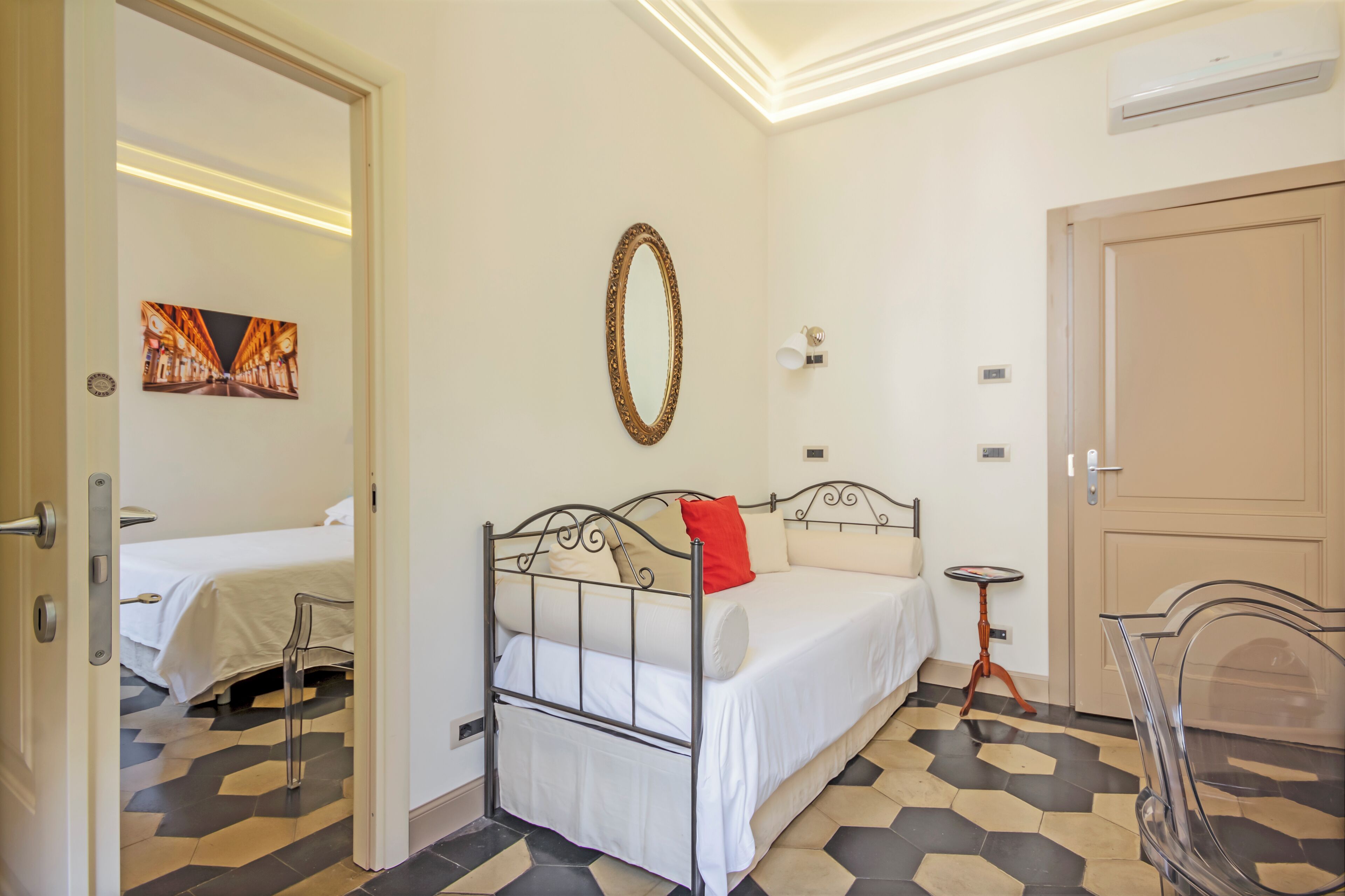 Une chambre d’hôtel avec un lit, un miroir, une petite table et une porte.