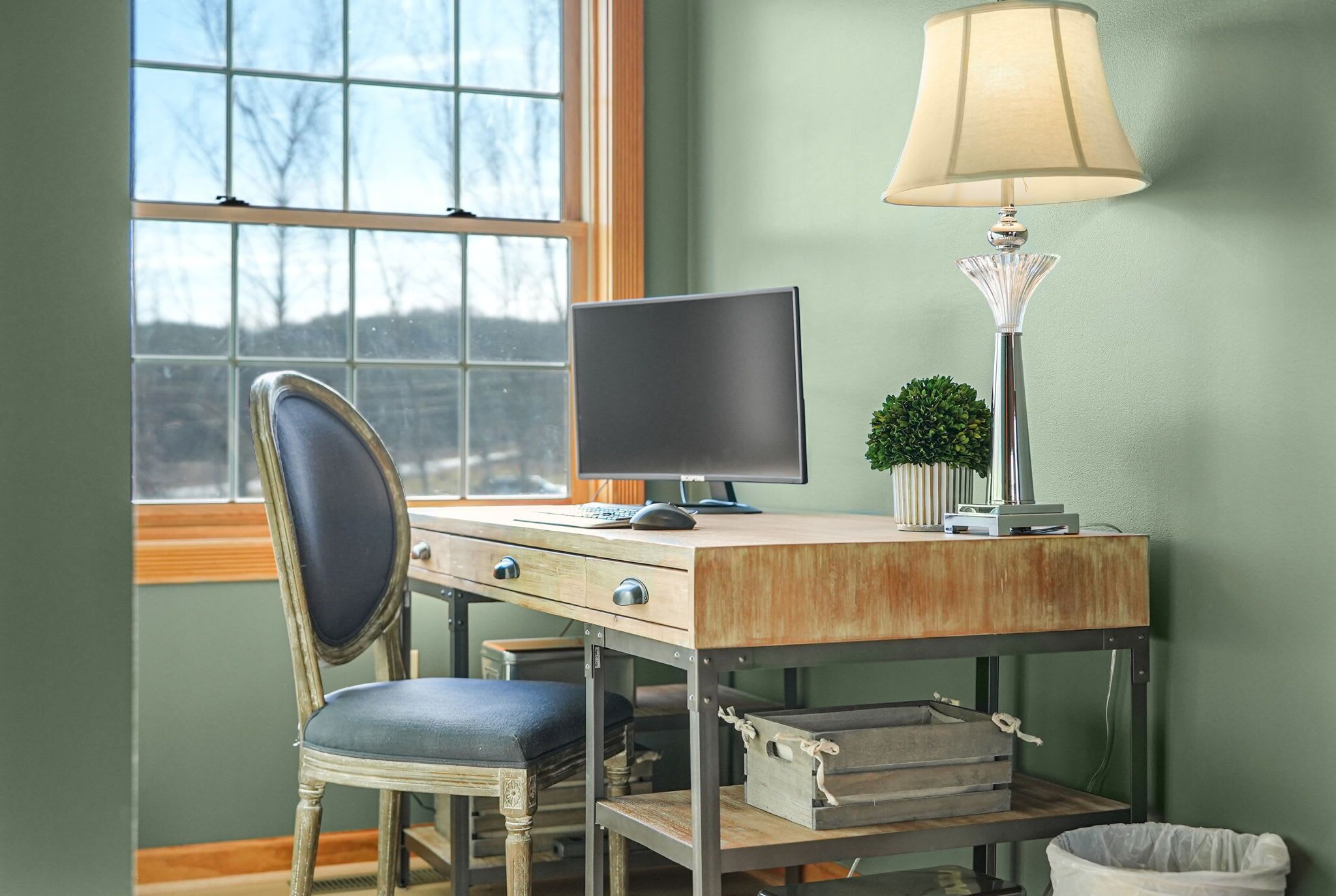A workspace with a desk, chair, computer, lamp, and a small plant.