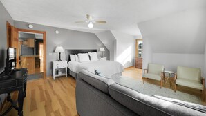 Une chambre à coucher comprenant un lit, des tables de chevet, un bureau, une chaise et un ventilateur de plafond.