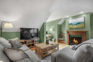 Een woonkamer met een flatscreen televisie, een open haard en een groene wand.