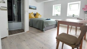 A modern bedroom with a bed, a desk, and a chair. There are windows and a door leading to another room. - SILONCE Hotel Bilstein - Lennestadt (Lennestadt)
