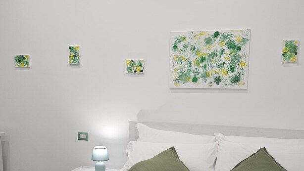 Une chambre moderne avec une couvre-lit verte, des oreillers blancs et une couverture verte. Des serviettes blanches pliées sont posées sur le lit.