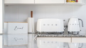 A kitchen with white appliances, including a bread maker and a coffee maker, on a granite countertop. - Haven Waters 8 on the lakefront (Forster)
