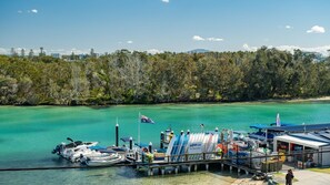 A marina with boats docked, a pier extending into turquoise water, and a forested background.