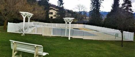 Un parque con una cerca de madera blanca, un pérgola blanca y una banca.