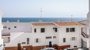 A coastal residential area with white buildings, a visible antenna, and a clear view of the sea.