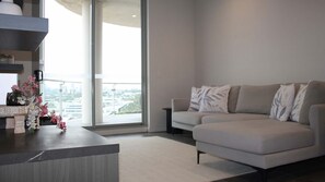 Ein modernes Wohnzimmer mit einer Couch, einem Couchtisch und Blick auf eine Stadtlandschaft durch große Fenster.