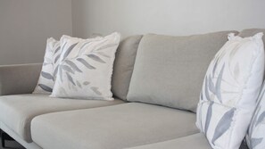 Ein Sofa mit zwei Kissen, eines mit einem Blattmuster und das andere schlicht.
