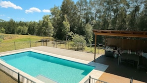 A swimming pool with a wooden deck, a barbecue area, and a fenced yard with trees. - Casa Sangiovese | In the Heart of the Hunter Valley (Pokolbin)
