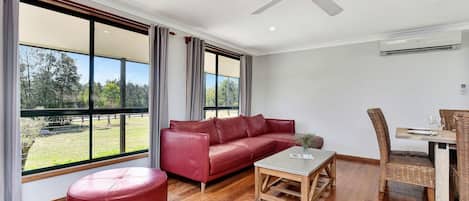 Una sala de estar moderna con un sofá de cuero, una mesa de centro de madera y un comedor con sillas de mimbre.