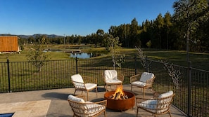An outdoor seating area with wicker chairs and a fire pit, overlooking a golf course and a body of water. - Casa Sangiovese | In the Heart of the Hunter Valley (Pokolbin)