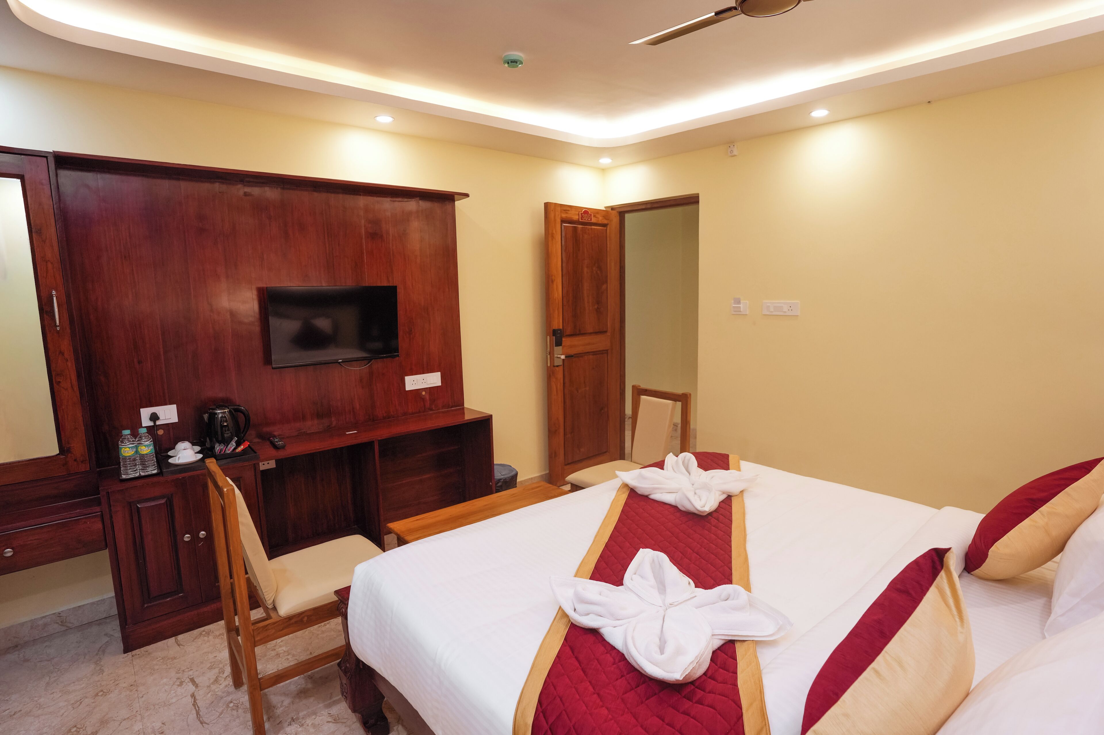 Una habitación de hotel con cama, escritorio, silla, televisor y armario.