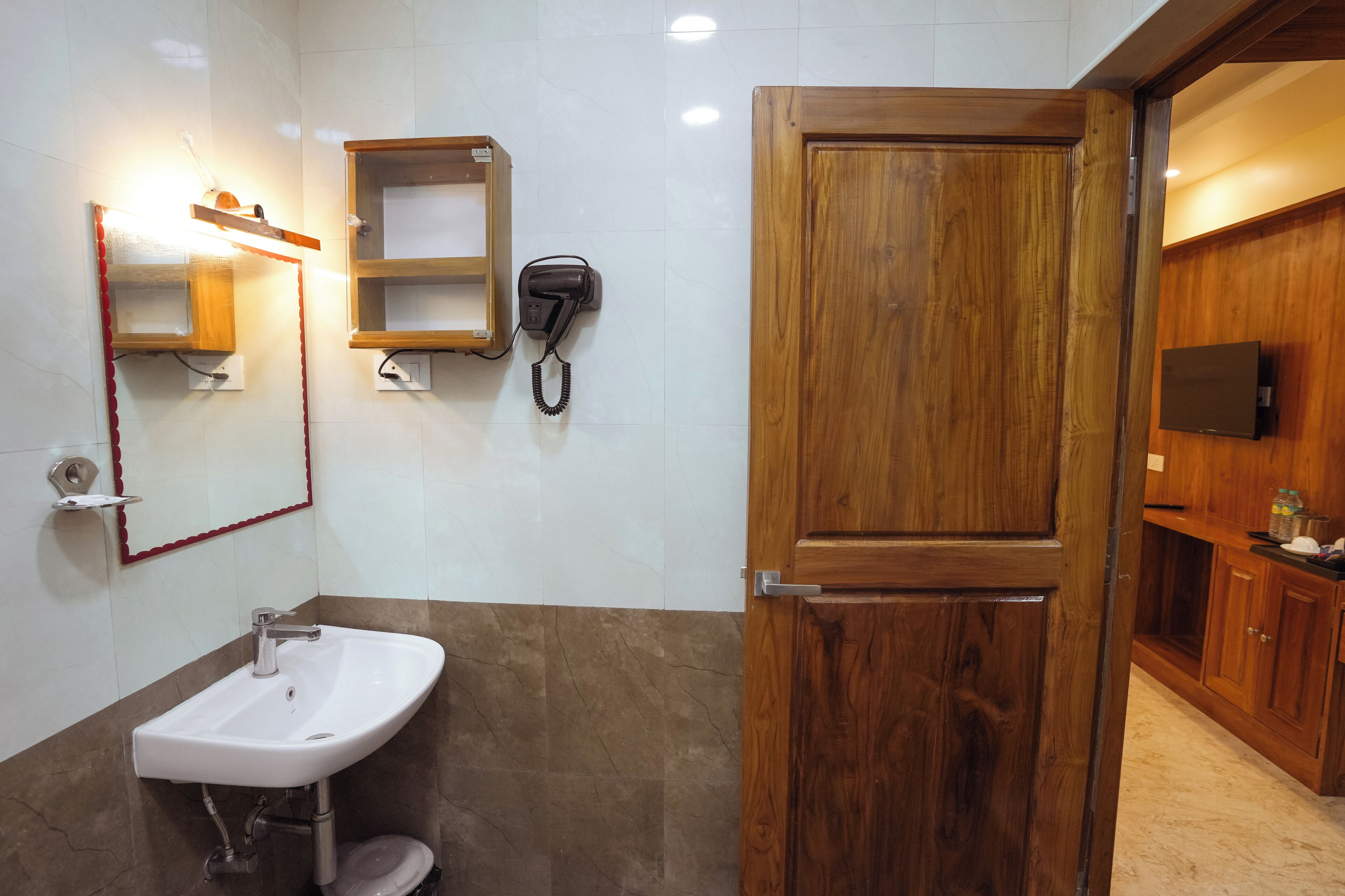 Un baño con lavamanos, espejo, teléfono y puerta de madera.