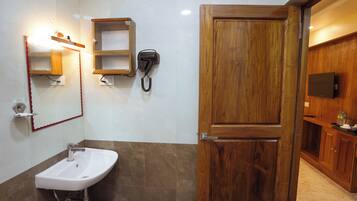 Un baño con lavamanos, espejo, teléfono y puerta de madera.