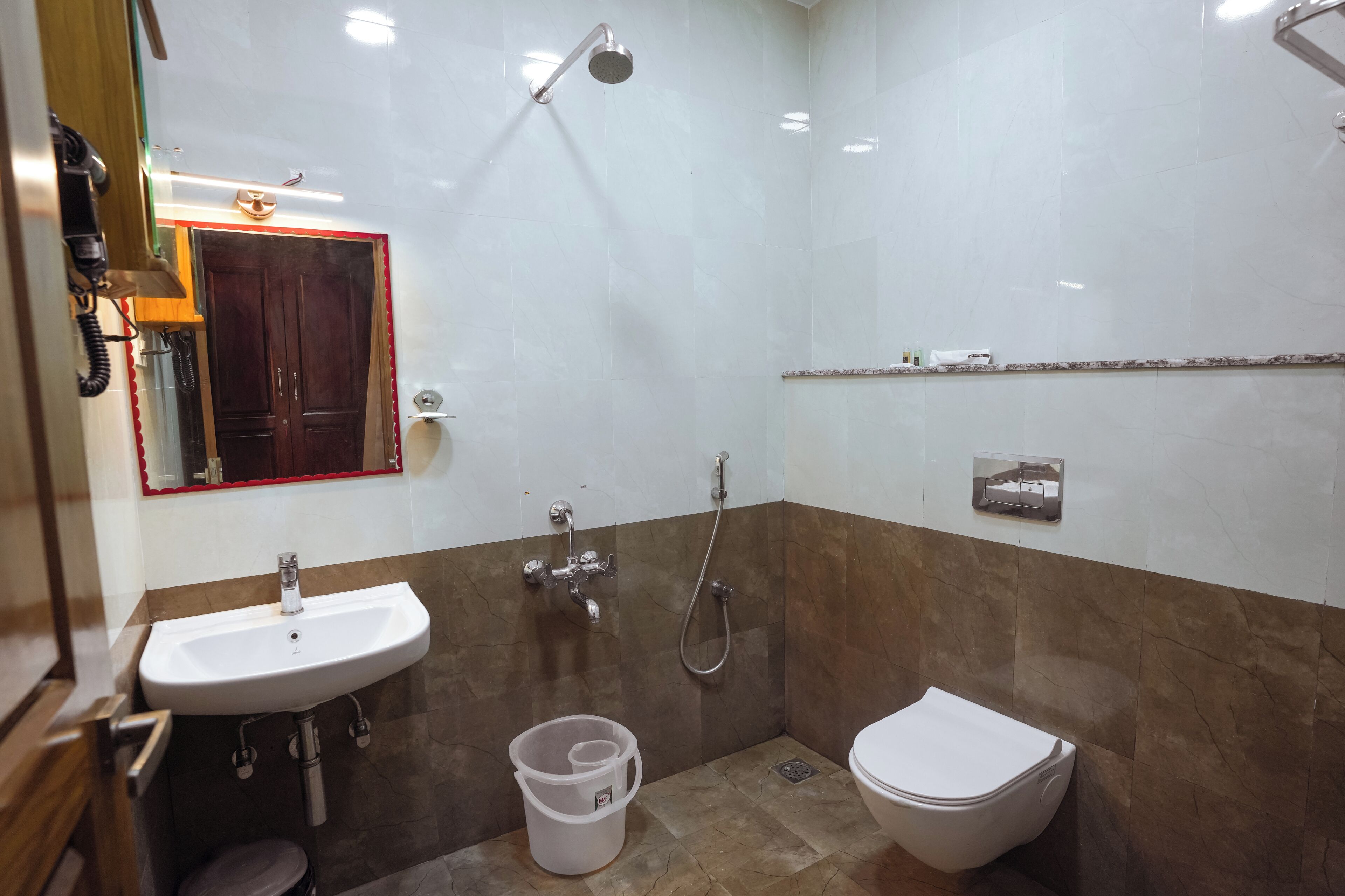 Un baño con lavamanos, inodoro, ducha y un espejo con marco rojo.
