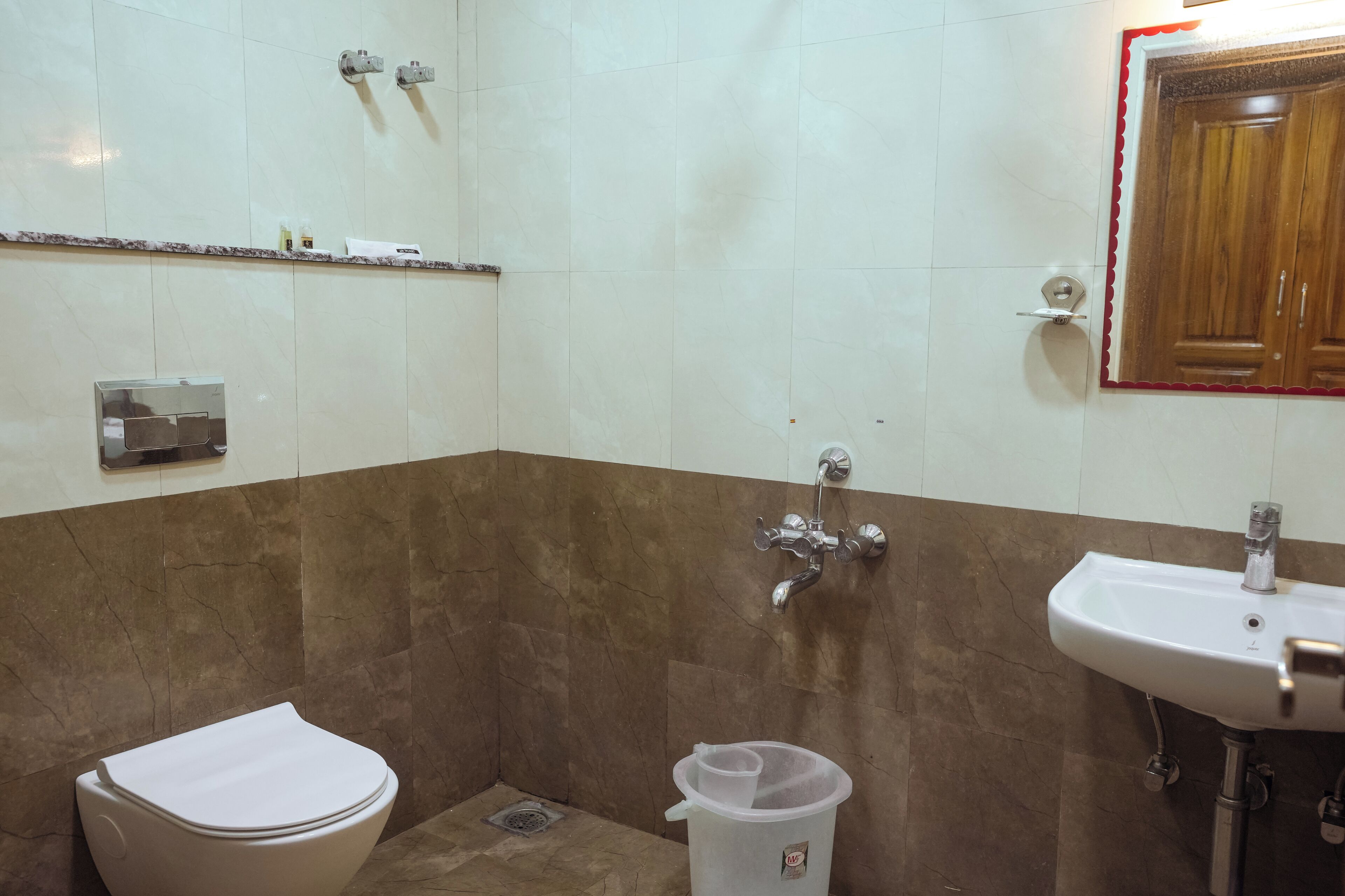 A bathroom with a toilet, a sink, a shower, and a mirror.