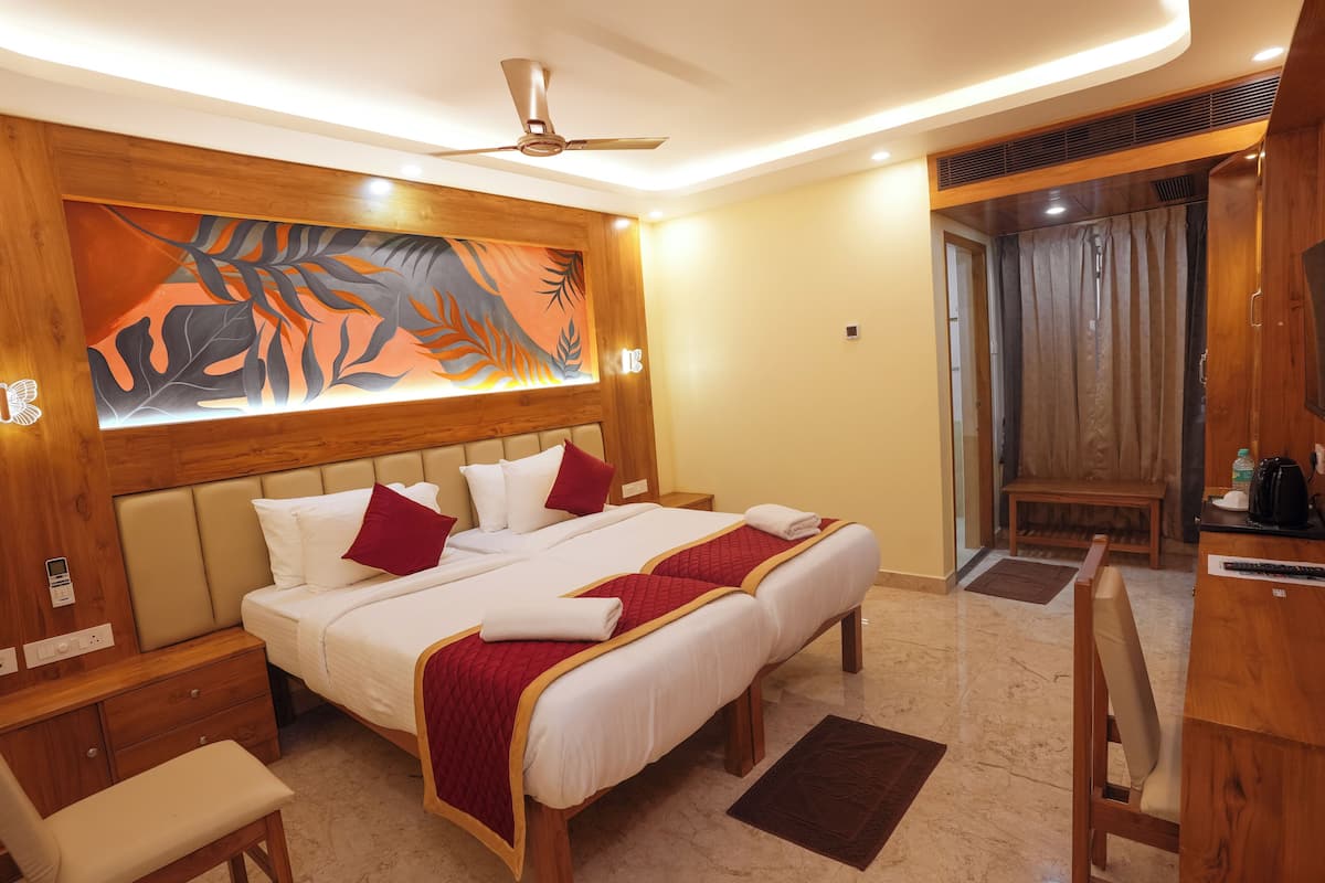 A hotel room with a large bed, a desk, a chair, a bench, and a painting on the wall.