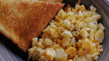 A bowl containing scrambled eggs and toasted bread.