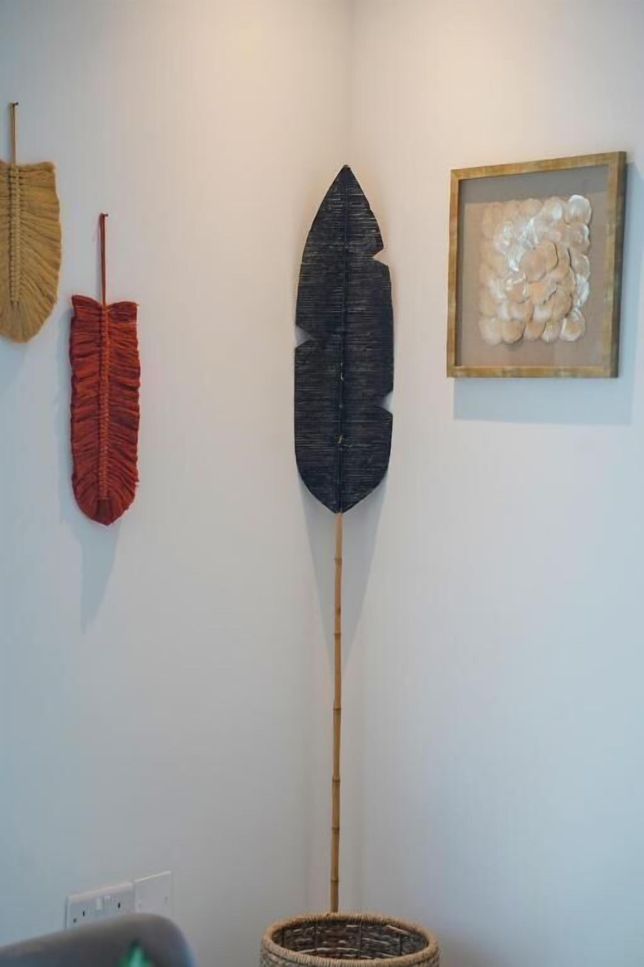 A room with a large feather decoration, a framed artwork, and a woven basket.
