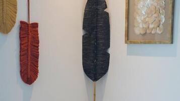 A room with a large feather decoration, a framed artwork, and a woven basket.