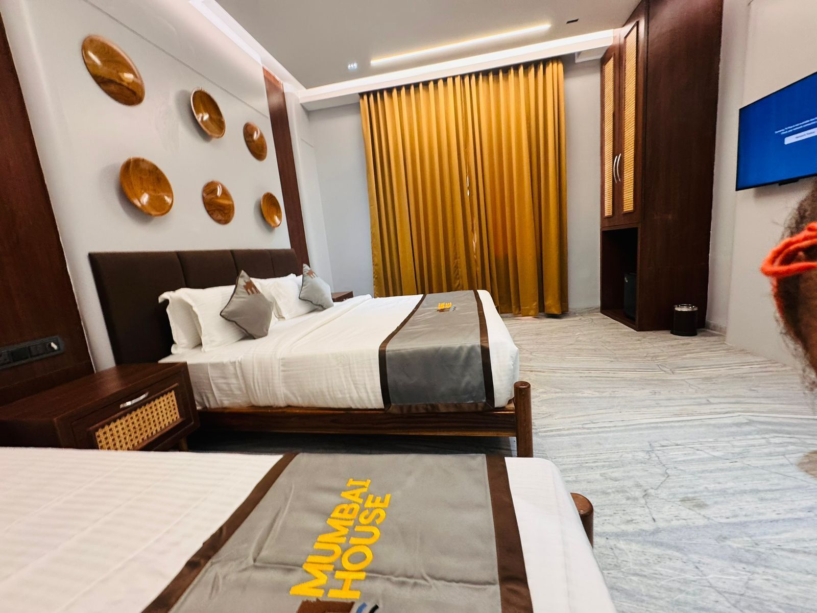 A hotel room with a bed, a TV, and a curtain.