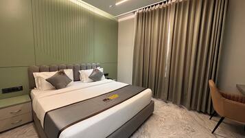Una habitación de hotel moderna con una cama grande, un ventilador de techo y vistas al exterior a través de cortinas.