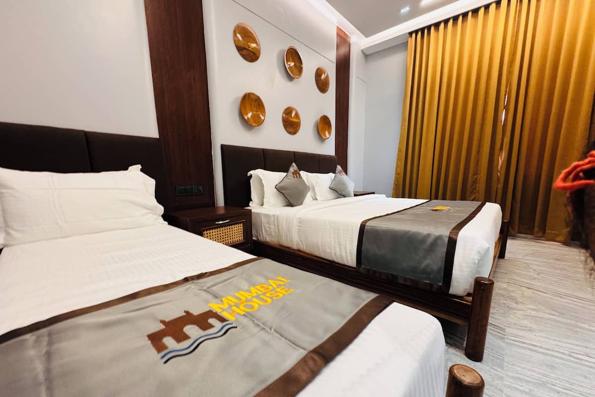 Habitación de hotel con dos camas, cabecero de madera, pared con adornos circulares y una cortina.