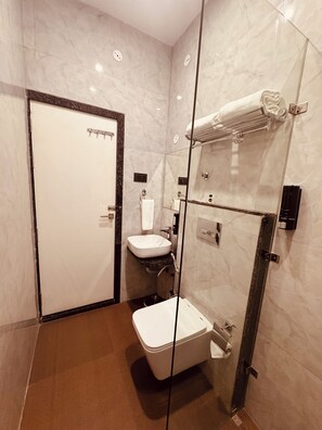 Ein modernes Badezimmer mit einer Glaskabine zur Dusche, einer weißen Toilette und einem Waschbecken.